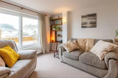a living room with a couch and a large window at Looe sea view sleeps 2 free parking in Looe