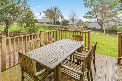 a wooden table and chairs on a wooden deck at 2 Bed in Tywardreath oc-d34709 in Tywardreath