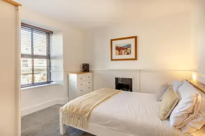 a white bedroom with a bed and a fireplace at 2 Bed in Newquay oc-j32859 in Newquay
