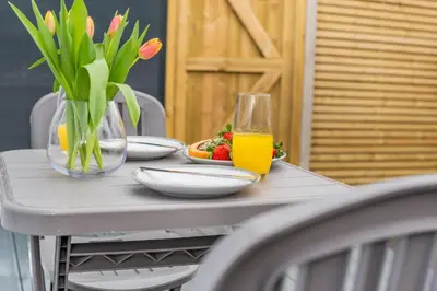 a table with a vase of flowers and a glass of juice at 1 Bed in Newquay oc-l28083 in Newquay