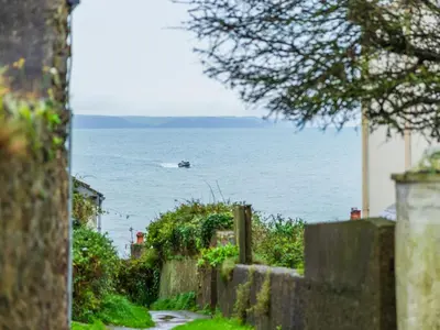 a small boat in the water with a fence at Holiday Home Zion by Interhome in Gorran Haven