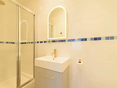 a white bathroom with a sink and a shower at Apartment No-4 Ocean Heights by Interhome in Mevagissey