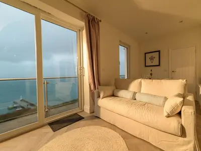 a living room with a couch and a large window at Apartment No-4 Ocean Heights by Interhome in Mevagissey