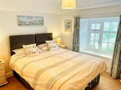 a bedroom with a large bed with a window at Cornwall Coastal Cottage - Beautiful & Stunning in Perranporth