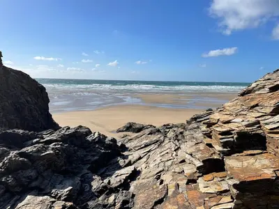 a beach with rocks and the ocean in the background at Cornwall Coastal Cottage - Beautiful & Stunning in Perranporth