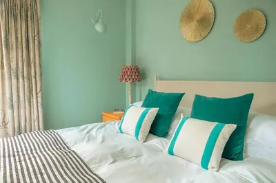 a bed with green and white pillows on it at Tredethick Farm Cottages in Lostwithiel