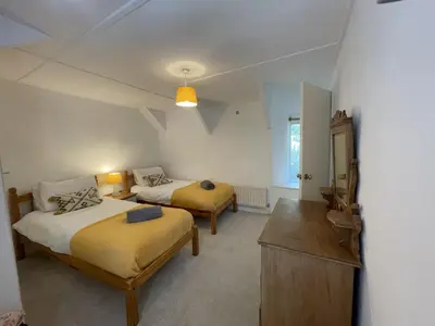 a bedroom with two beds and a dresser in it at The Brewhouse Boscastle Harbour in Boscastle