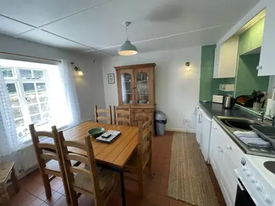 a kitchen with a wooden table with chairs and a kitchen counters at The Brewhouse Boscastle Harbour in Boscastle