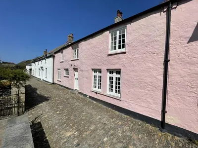 a row of pink buildings on a cobblestone street at The Brewhouse Boscastle Harbour in Boscastle