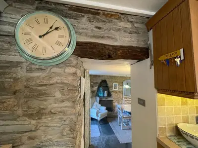 a clock hanging on a stone wall in a room at Sandown St Teath 3 bed sleeps 6 in Saint Teath