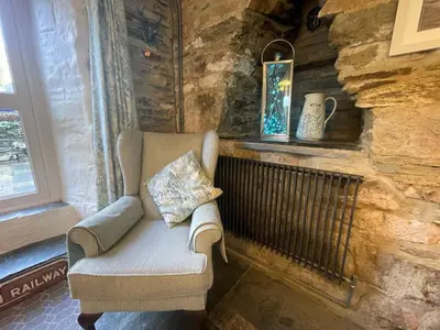 a chair sitting in a room with a stone wall at Sandown St Teath 3 bed sleeps 6 in Saint Teath