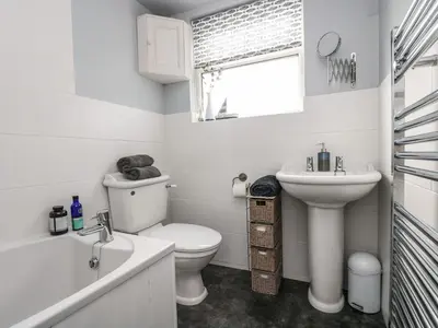 a white bathroom with a toilet and a sink at Driftwood Cottage in Helston