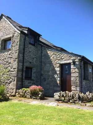 an old stone building with a door and flowers at Barn Cottage in Saint Breward