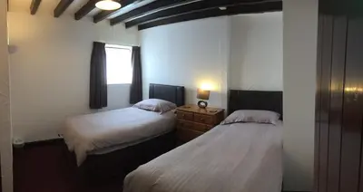 a bedroom with two beds and a window at Barn Cottage in Saint Breward