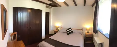 a bedroom with a bed and two tables and two lamps at Barn Cottage in Saint Breward