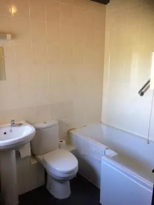 a bathroom with a toilet and a tub and a sink at Barn Cottage in Saint Breward