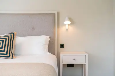 a bedroom with a bed and a side table with a lamp at Allora in Carbis Bay