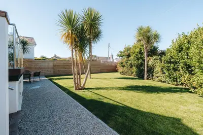 a backyard with palm trees and a fence at Allora in Carbis Bay