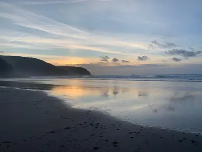 a beach with the reflection of the sky in the water at Seabrook Lodge in Newquay