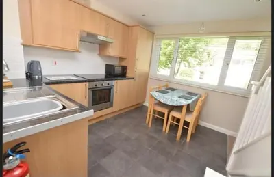 a kitchen with a table and a sink and a window at Seabrook Lodge in Newquay