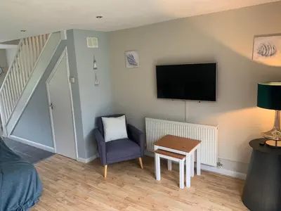 a living room with a tv and a blue chair at Seabrook Lodge in Newquay