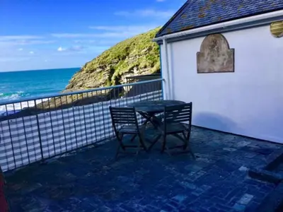 a table and two chairs on a balcony with the ocean at Praxis Trebarwith Strand in Treknow