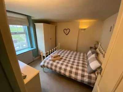 a small bedroom with a bed with a checkered blanket at Praxis Trebarwith Strand in Treknow