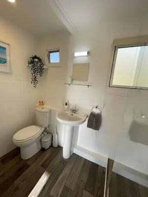 a white bathroom with a toilet and a sink at Villa 22 Lanteglos Hotel in Lanteglos