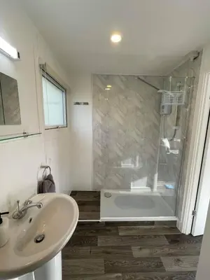 a white bathroom with a shower and a sink at Villa 22 Lanteglos Hotel in Lanteglos