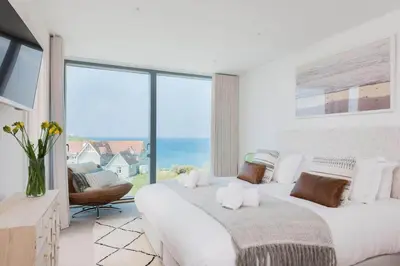 a white bedroom with a large bed and a large window at Beachfront Townhouse Lovely Sea Views Newquay in Newquay