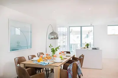 a dining room with a wooden table and chairs at Beachfront Townhouse Lovely Sea Views Newquay in Newquay