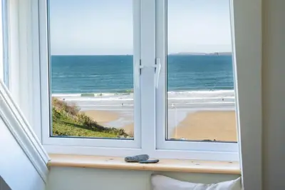 an open window with a view of the beach at Spacious House Sea Views Opposite Beach in Newquay