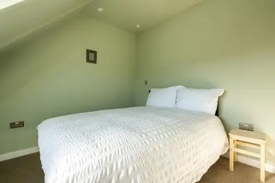a bedroom with a white bed and a small table at Spacious House Sea Views Opposite Beach in Newquay