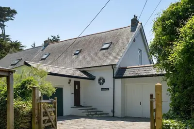 a white carriage house with a garage at Beautiful Home with Pool Overlooking Camel Estuary in Roche