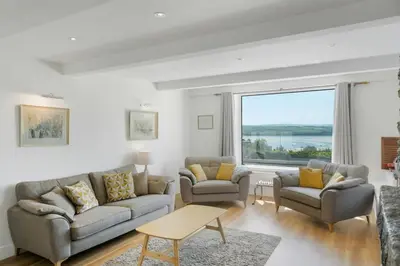 a living room with two couches and a large window at Beautiful Home with Pool Overlooking Camel Estuary in Roche