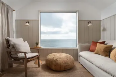 a living room with a couch and a large window at Cosy Beach House on the Seafront Porthleven in Porthleven