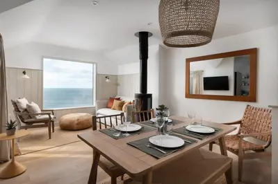 a living room with a table and a fireplace at Cosy Beach House on the Seafront Porthleven in Porthleven