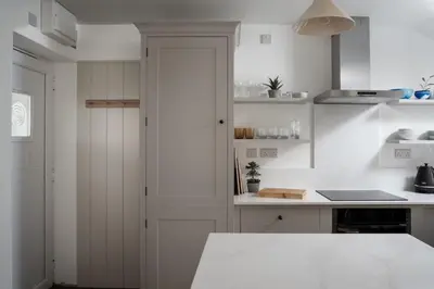 a kitchen with white walls and a white door at Cosy Beach House on the Seafront Porthleven in Porthleven