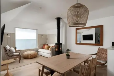 a living room with a table and a fireplace at Cosy Beach House on the Seafront Porthleven in Porthleven
