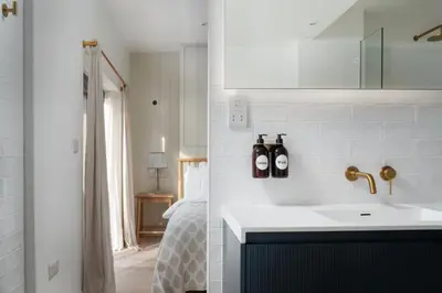 a bathroom with a sink and a bedroom with a bed at Cosy Beach House on the Seafront Porthleven in Porthleven