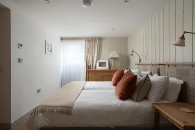 a bedroom with a large white bed with pillows at Cosy Beach House on the Seafront Porthleven in Porthleven