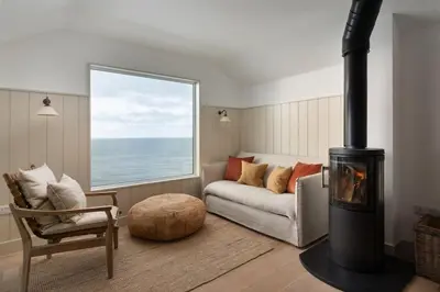 a living room with a couch and a fireplace at Cosy Beach House on the Seafront Porthleven in Porthleven