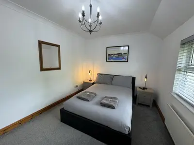 a bedroom with a bed and a chandelier at The Meadows St Teath 4 bed sleeps 7 in Saint Teath