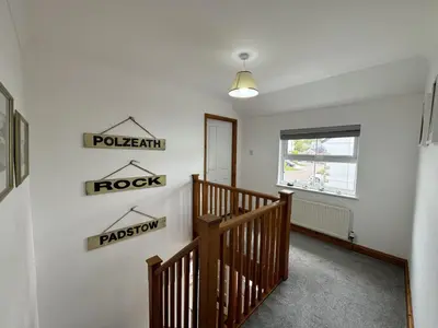 a hallway with a wooden staircase and signs on the wall at The Meadows St Teath 4 bed sleeps 7 in Saint Teath