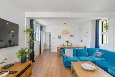 a living room with a blue couch and a table at Beautiful Home with Sea Views & Parking in Porthtowan