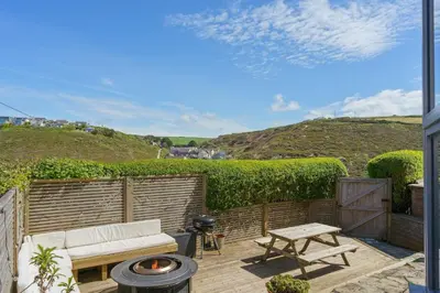 a patio with a white couch and a fire pit at Beautiful Home with Sea Views & Parking in Porthtowan