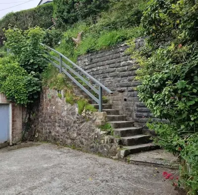 a set of stone stairs with a metal railing at Beautiful Home with Sea Views & Parking in Porthtowan