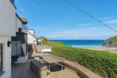 a patio with a bench and the ocean in the background at Beautiful Home with Sea Views & Parking in Porthtowan