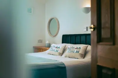 a bedroom with a bed with two pillows and a mirror at The Granary Couples & Families Retreat Near St Ives, Pet-Free in St Ives