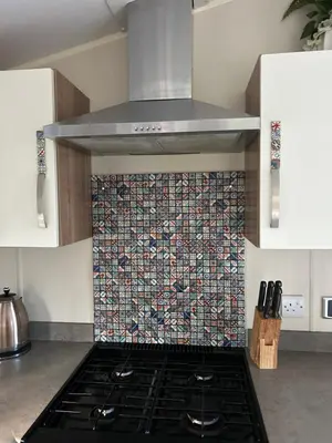 a kitchen with a stove with a mosaic wall at Cabin in the Woods in Saint Erth